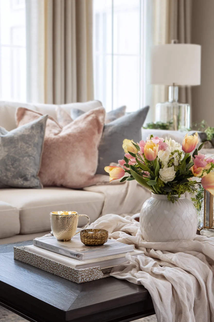 Soft blush pink linen runner draped across a wooden coffee table under a large vase of white hydrangeas.